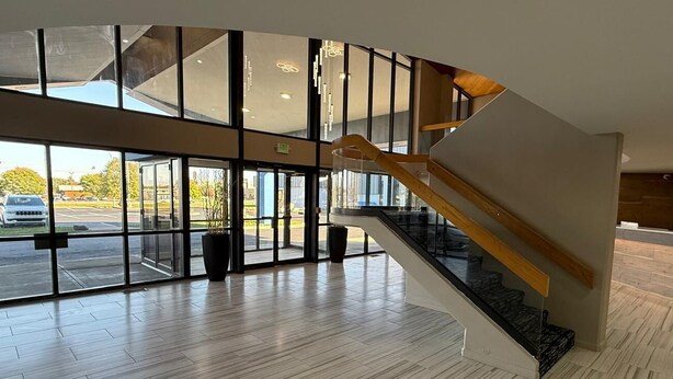 Un hall d’entrée spacieux, doté d’un escalier en colimaçon, de grandes fenêtres et d’une vue sur le parking.