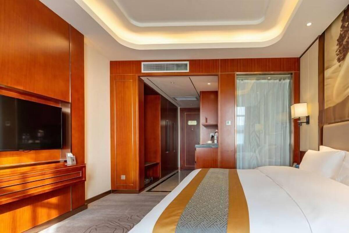 Hotelkamer met een groot bed, een flatscreen televisie, houten lambrisering, een badkamer en uitzicht op de stad.