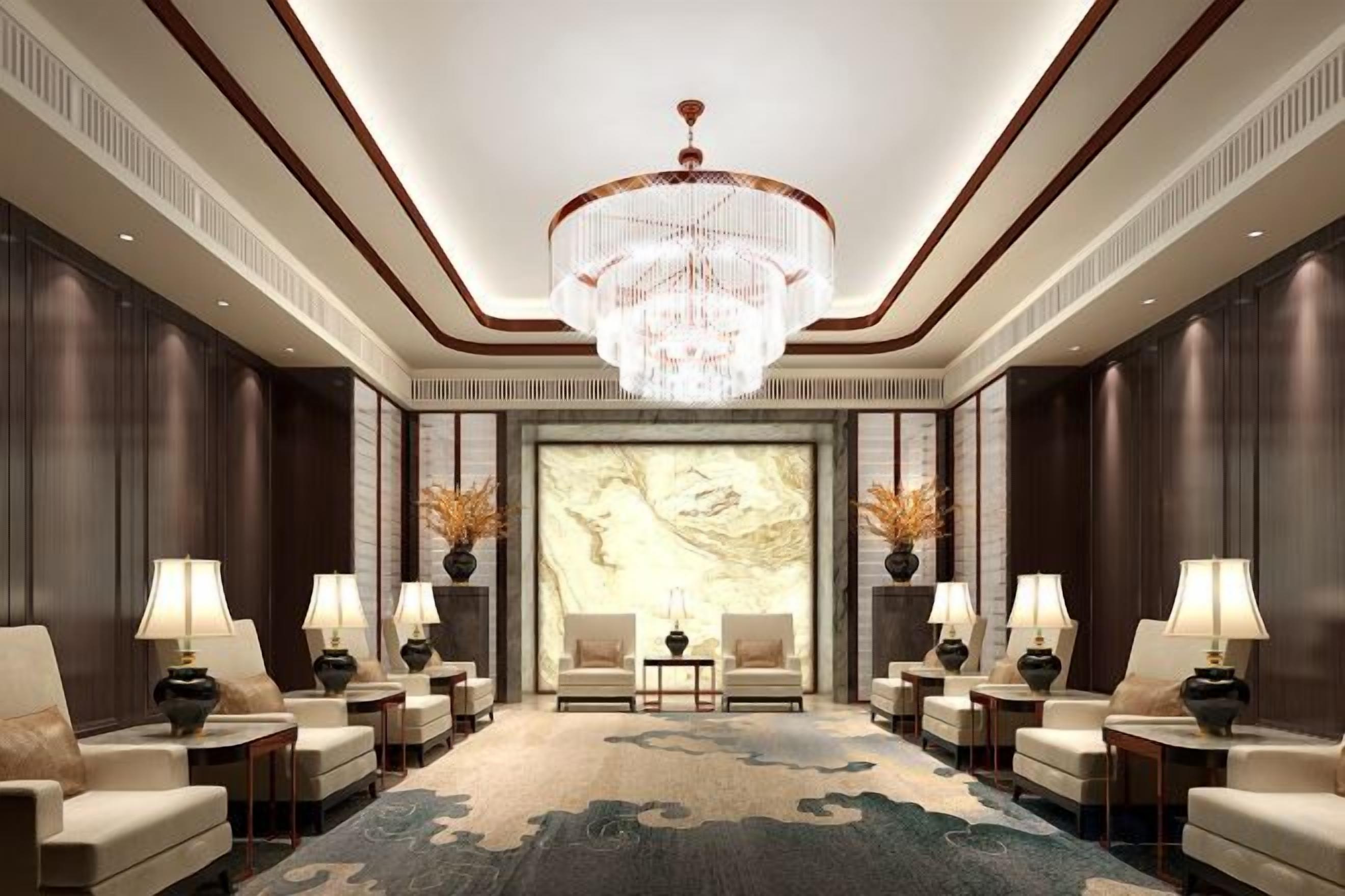 A hotel lobby with a large chandelier, seating area, and a large wall mural.