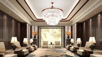 A hotel lobby with a large chandelier, seating area, and a large wall mural.