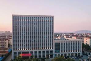 Un edificio de varios pisos con un diseño arquitectónico moderno, que presenta un techo plano y una fachada simétrica.