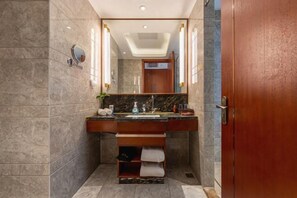 A bathroom with a marble wall, a wooden vanity, a mirror, and a towel rack. - Qingdao Haina Baichuan Hotel (Pingdu)