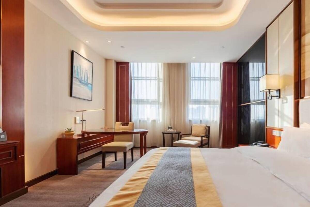 Een hotelkamer met een bed, bureau, stoelen en een groot raam.