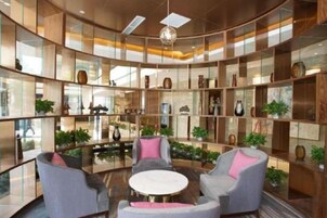 A modern interior with a circular seating area, glass partitions, and shelves with decorative items.