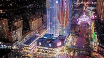A high-rise building with a distinctive vertical design, surrounded by other buildings and a busy street at night.