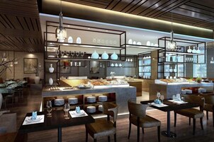 Un interior de restaurante moderno con una isla central, mesas de comedor y lámparas colgantes.