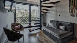 A modern living room with a sofa, two wicker chairs, a staircase, and a large window. - Tulum Stylish 2BR Penthouse W/private Terrace, Grill & Pool (Tulum)