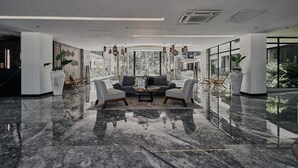 A spacious lobby with a marble floor, a sofa set, and large windows offering a view of greenery. - Tulum Stylish 2BR Penthouse W/private Terrace, Grill & Pool (Tulum)