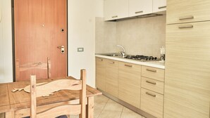 Eine moderne Küche mit Holzsäulen, einem Edelstahl-Spülbecken und einem Esstisch mit Stühlen.