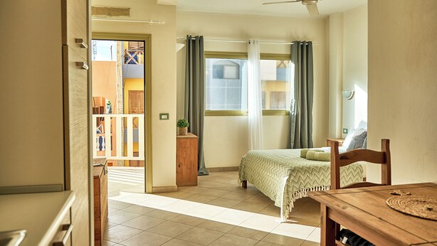 Ein Schlafzimmer mit einem Bett, einem Nachttisch aus Holz, einem Tisch und einem Deckenventilator.