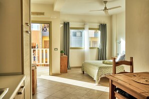 Une chambre à coucher avec un lit, une table de chevet en bois, une table et un ventilateur de plafond.