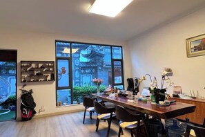 A dining area with a long table, chairs, and a view of traditional architecture through large windows. - Zuimei Dali Boutique Inn (Dali City)