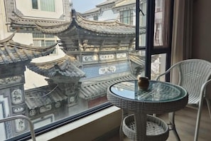 A balcony with traditional Chinese architectural elements, a round table with a bowl, and wicker chairs. - Zuimei Dali Boutique Inn (Dali City)