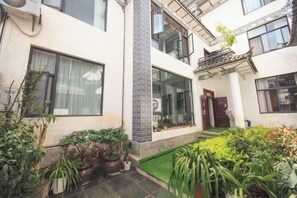 Un edificio residenziale con cortile interno, piante in vaso e un piccolo prato.