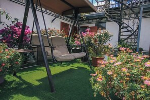 An outdoor seating area with a swing chair, a table, and potted plants. - Zuimei Dali Boutique Inn (Dali City)