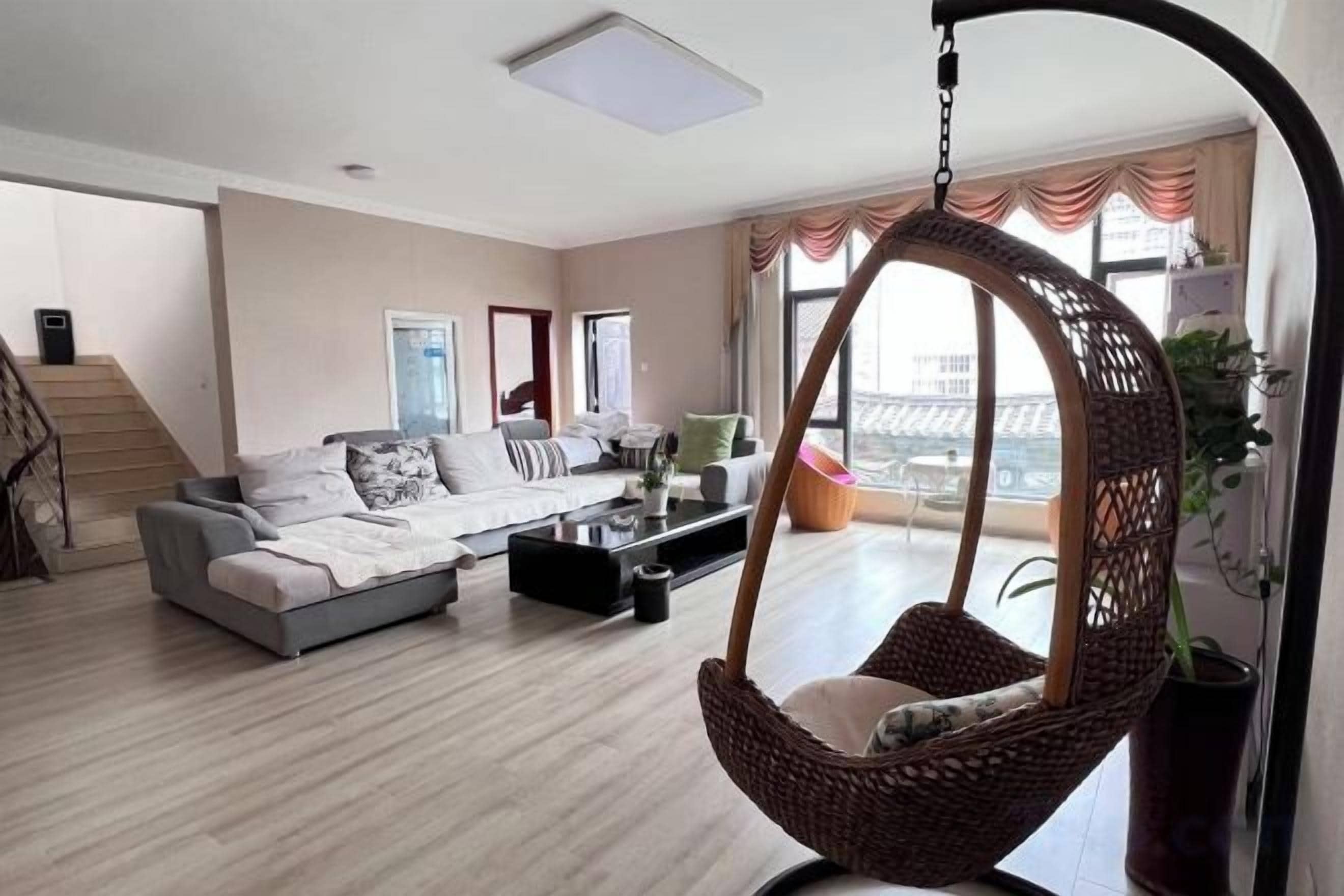 A modern living room with a sofa, coffee table, and a hanging chair.