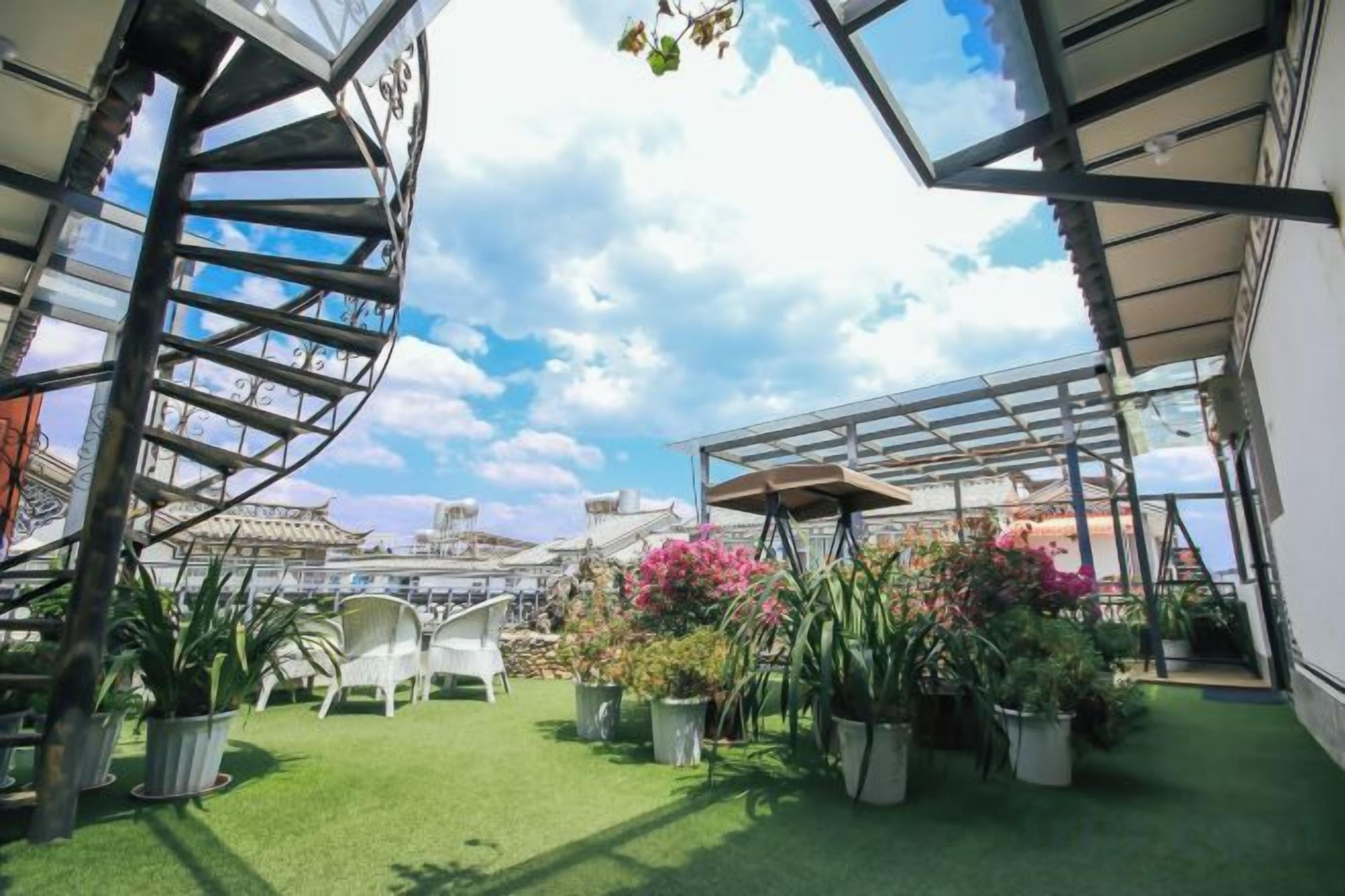 Un jardin sur le toit agrémenté d’un escalier en colimaçon, de plantes en pot et de coins salon extérieurs.