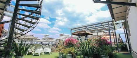 A rooftop garden with a spiral staircase, potted plants, and outdoor seating.