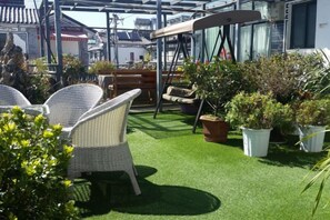 An outdoor seating area with wicker chairs, a swing, and potted plants. - Zuimei Dali Boutique Inn (Dali City)