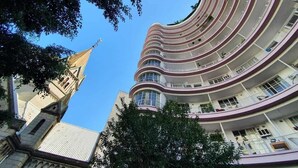 Un edificio de varios pisos con fachada curva, balcones y una torre del reloj.