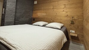 A bedroom with a bed, wooden walls, and a stone accent wall.
