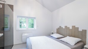 A modern bedroom with a large bed, a window, and a shower area. - Chalet du Petit-Bouchot : cosy, private spa, 2p (Rochesson)