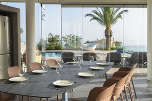 A dining table set for six with chairs, overlooking a pool and palm trees.