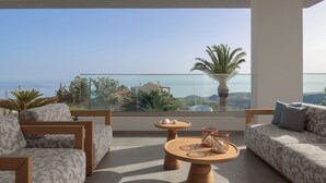 A modern balcony with a clear view of the sea, furnished with a sofa, chairs, and a round table. - Villa Kalliston - 4000m2 of Elevated Living (Rethymno)