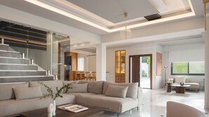 A modern living room with a sofa, coffee table, and a staircase leading to an upper level. - Villa Kalliston - 4000m2 of Elevated Living (Rethymno)