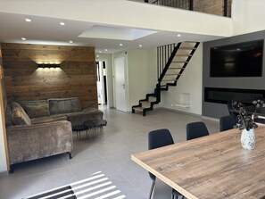 Relax in a stylish living space with a sofa, chairs, and dining table, plus a staircase to an upper level.