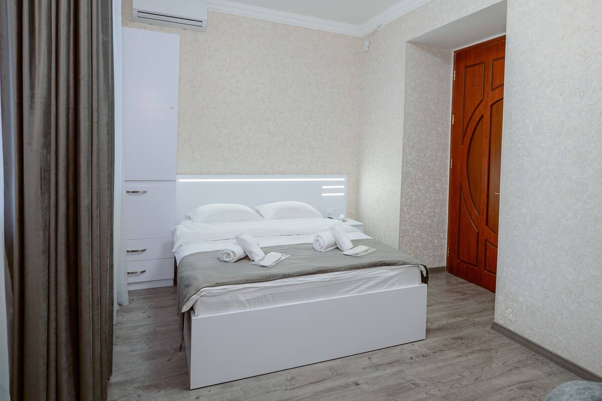 A neatly arranged bedroom with a bed, a wardrobe, and a door.