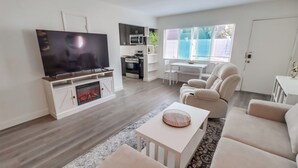 A modern living room with a flat-screen TV, a fireplace, a dining area with a table and chairs, and a sofa. - Majestic Coastal Retreat in Coronado (Coronado)