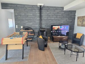 Un salon avec un baby-foot, une télévision, un canapé et une table basse.