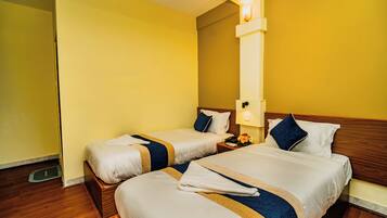 A hotel room with two beds, wooden headboards, and a nightstand with a lamp.