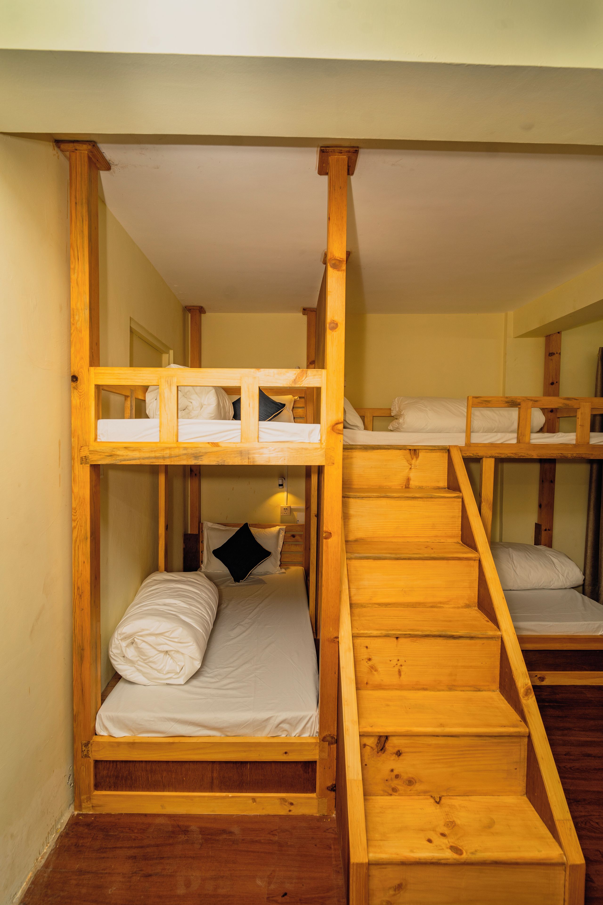 Habitación con literas de varios niveles, estructura de madera y escalera que las conecta.