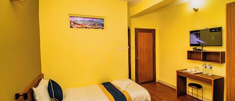 A hotel room with two beds, a desk, a TV, and a painting on the wall.