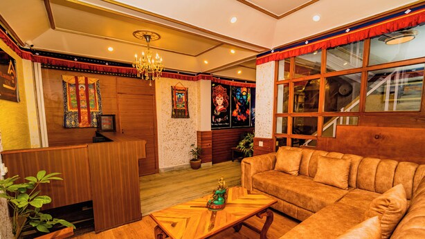 A cozy living room with a wooden coffee table, a sofa, and a chandelier. - Hotel Aashraya Home Pvt. Ltd.  (Kathmandu)