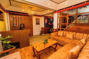A cozy living room with a wooden coffee table, a sofa, and a chandelier. - Hotel Aashraya Home Pvt. Ltd.  (Kathmandu)
