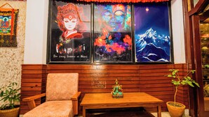 A room with a wooden bench, a small table, and a Buddha statue. - Hotel Aashraya Home Pvt. Ltd.  (Kathmandu)
