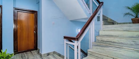 A staircase with marble steps and a wooden handrail leading to a landing.