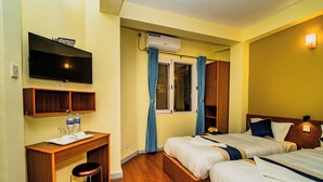 A hotel room with two beds, a desk with a chair, a television, and an air conditioning unit. - Hotel Aashraya Home Pvt. Ltd.  (Kathmandu)