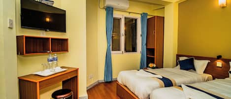 A hotel room with two beds, a desk with a chair, a television, and an air conditioning unit.