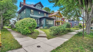 A two-story house with a front porch, a well-maintained lawn, and a sidewalk leading to the entrance. - Live in sophistication and elegance in your VRBO home (Rochester)