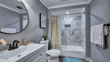 A bathroom with a white sink, a toilet, a bathtub, and a shower curtain.