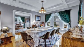 A dining area with a table set for six, a chandelier, and a view of the outdoors through large windows. - Live in sophistication and elegance in your VRBO home (Rochester)