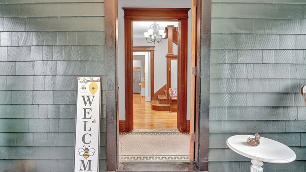 A wooden exterior with a welcome sign, a staircase, and a small table with a decorative item. - Live in sophistication and elegance in your VRBO home (Rochester)