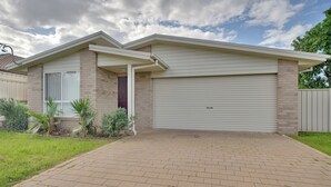 A single-story house with a garage door, a brick exterior, and a paved driveway.
