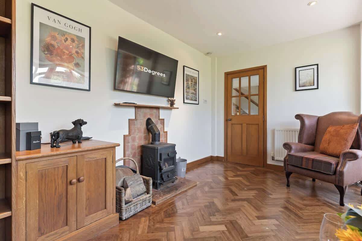 Een woonkamer met een houten kast, een open haard, een televisie en een leren fauteuil.