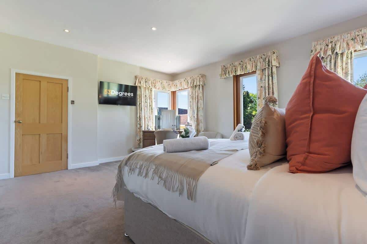 Une chambre à coucher avec un lit, des rideaux, une télévision et une porte.