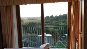 A bedroom with a bed, a balcony with a table and chairs, and a view of the countryside. - Room-orchard Manor, Fore Street, Nr Trur (Truro)